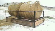 two bales of hay sitting on top of a wooden crate in the snow