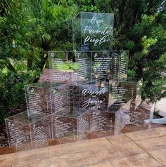 clear acrylic signs with names and dates on them sitting in front of some trees