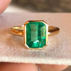 a close up of a person holding a ring with a green stone in the middle