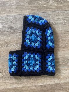 a blue and black crocheted dishcloth on top of a wooden floor next to a pair of scissors