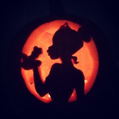 the silhouette of a woman holding a teddy bear carved into a pumpkin