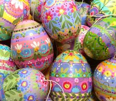 colorful painted easter eggs are piled on top of each other in a pile with twine string