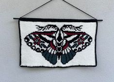 a crocheted wall hanging with a black and white moth on it's side