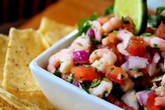 a white bowl filled with shrimp and veggies next to tortilla chips