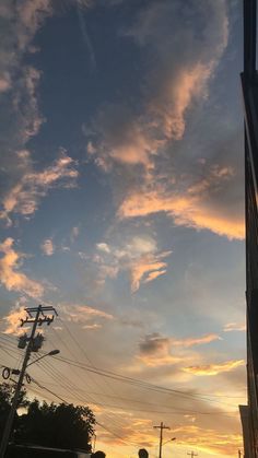 the sun is setting behind some buildings and telephone poles in front of a tall building