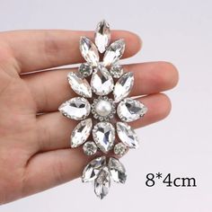 a hand holding a crystal brooch in it's palm