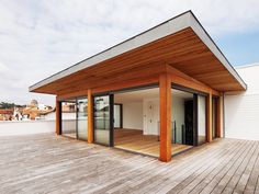 an empty wooden deck with sliding glass doors on the top floor and roof area in front of it