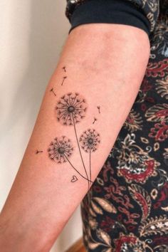 a woman's arm with a dandelion tattoo on it