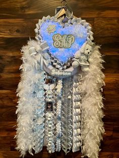 a blue and white heart with feathers hanging on a wall