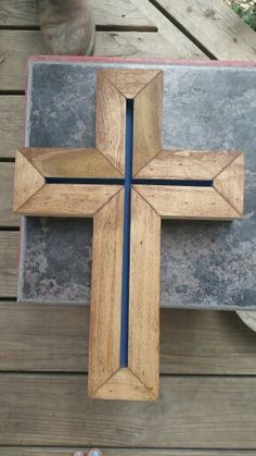 a wooden cross sitting on top of a table next to a potted planter