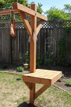 a wooden bench sitting on top of a grass covered yard next to a fence and tree