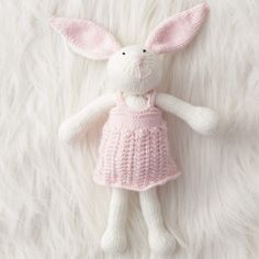 a knitted bunny doll laying on top of white fur