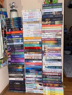 a stack of books sitting on top of a hard wood floor next to a wall