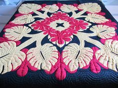 a quilted bedspread with pink and white flowers on it, sitting on a bed