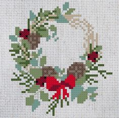 a cross stitch wreath with red flowers and green leaves