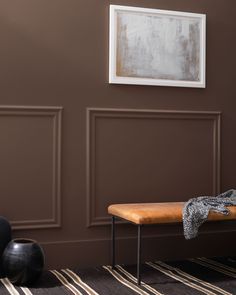 a wooden bench sitting in front of a wall with two black vases on it