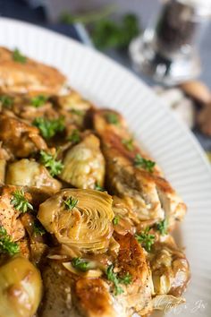 a white plate topped with chicken and artichokes