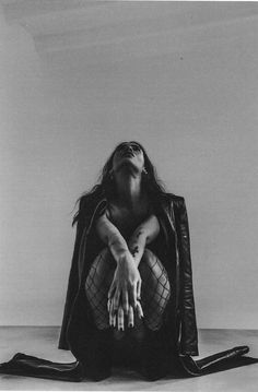 a black and white photo of a woman sitting on the floor with her hands up