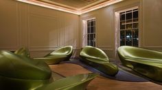 green chairs and tables in a room with windows