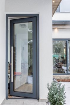 an open door on the side of a building with a potted plant next to it