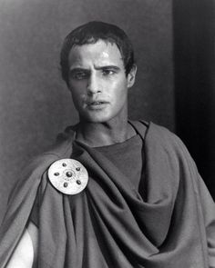 a black and white photo of a man dressed in roman garb with buttons on his chest