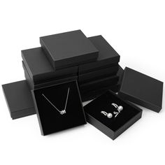 several black boxes with silver jewelry in them