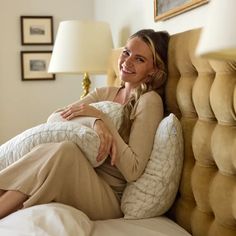 a woman laying on top of a bed next to a lamp