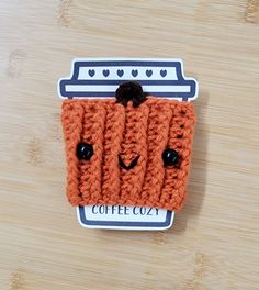 an orange crocheted coffee cosy sitting on top of a wooden table