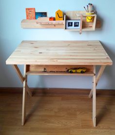 a wooden desk sitting on top of a hard wood floor next to a white wall