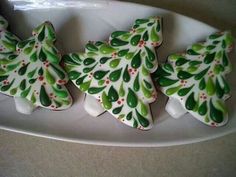 three decorated cookies in the shape of christmas trees