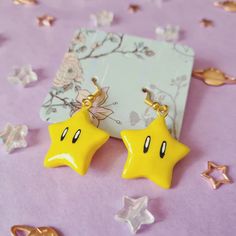 two yellow star shaped earrings sitting on top of a purple table covered with confetti