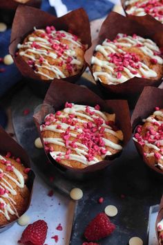 some cupcakes with white frosting and raspberries