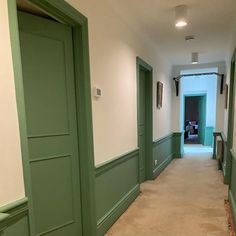 an empty hallway with green doors and white walls