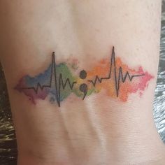 a watercolor heartbeat tattoo on the side of a woman's stomach, with colorful ink