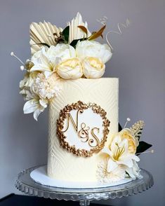 a wedding cake decorated with white flowers and monogrammed initials