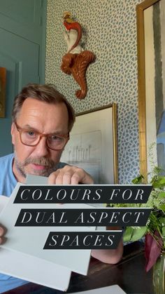 a man sitting at a table holding up a sign that says colours for dual aspects spaces