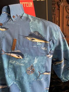 "CLEARWATER OUTFITTERS Men's Short Sleeve Fishing Shirt size Large, 100% Cotton Deep Sea Fish Pattern Print Sportsmans Gift for Him. Early 2000's Clearwater Outfitters mens blue background with an all-over deep water sport fish pattern print shirt. 100% cotton, short sleeves with a fold over button-down collar, single patch pocket and a rounded hem line. Perfect gift for the sports fisher in your life. MEASUREMENTS: Chest (pit to pit x2):  48in Shoulder (across back seam to seam):  20in Sleeve (shoulder seam to end of cuff):  10in Length (bottom of collar to hem):  30in Measurements taken while garment was lying flat. Vintage garment sized run different than today's clothing so please check and compare measurements.  This shirt is tagged L(large). Please check your own measurements to assu Casual Fishing Shirt With Pockets, Deep Sea Fish, Buy Clothes Online, Fish Pattern, Fish Man, Water Sport, Fish Patterns, Deep Water, Todays Outfit