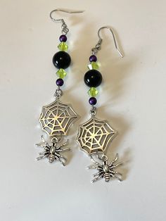 Adorable spider dangle earrings approx. 3.75" long overall. Made with nickel free hooks and findings. Comes in an organza pouch. Spider and spiderweb charms are metal. Black, purple and green are glass beads. Green Halloween Dangle Earrings, Gothic Earrings Diy, Themed Black Dangle Jewelry, Halloween Jewelry Diy Ideas, Halloween Jewelry Diy, Fall Bead, Diy Jewelry Unique, Gothic Earrings, Diy Bracelet Designs