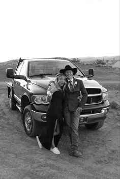 black and white photograph of two people standing next to a truck in the middle of nowhere