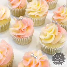 cupcakes with pink and yellow frosting on white paper, decorated with pearls