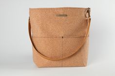 This vegan handbag is made from sustainably sourced cork, also known as vegan leather! The perfect vegan gift, our cork bags are beautiful, naturally waterproof, stylish and sustainable. Our casual, front pocket bucket bag in cork fabric is the perfect carryall for everyday use. The single strap makes it easy to swing over your shoulder; or add a longer, crossbody strap and easily transition to hands-free shopping, sightseeing and errands. Conveniently placed pockets, durable construction and a Eco-friendly Bucket Shoulder Bag In Natural Fiber, Eco-friendly Jute Shoulder Bag For Travel, Eco-friendly Natural Bucket Bag With Adjustable Strap, Eco-friendly Large Capacity Jute Bucket Bag, Cork Bags, Cork Handbag, Aesthetic Tote Bag, Cork Bag, Casual Tote Bag