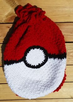 a red and white crocheted hat with a black eyeball on the front