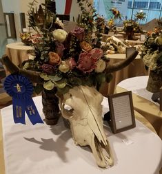 an arrangement of flowers in a vase on top of a table with a blue ribbon