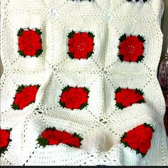 a crocheted blanket with red roses on it