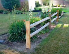 a wooden fence in the middle of a yard with flowers and plants growing on it