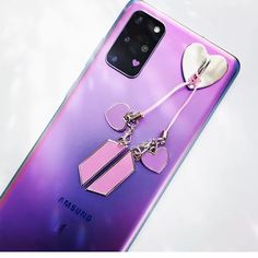 a samsung phone with two charms attached to it