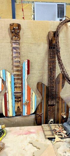 two guitars made out of wood sit on a table next to other art pieces and materials