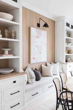 a dining room with white cabinets and wooden shelves filled with plates, bowls and vases