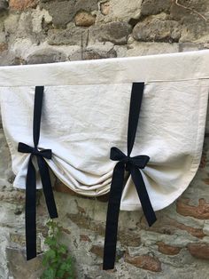 a white towel hanging on the side of a brick wall with black ribbon tied around it