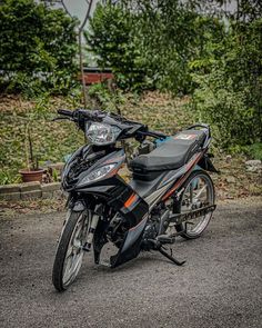 the motorcycle is parked on the side of the road next to some bushes and trees